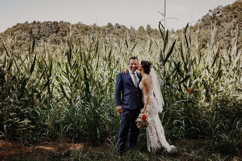 bride and groom in front of rows of corn