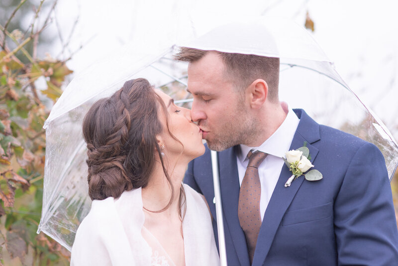 photo of a couple kissing  on a rainy day  underneath and umbrella photographed  by Austin TX based Wedding Photographer Lydia Teague