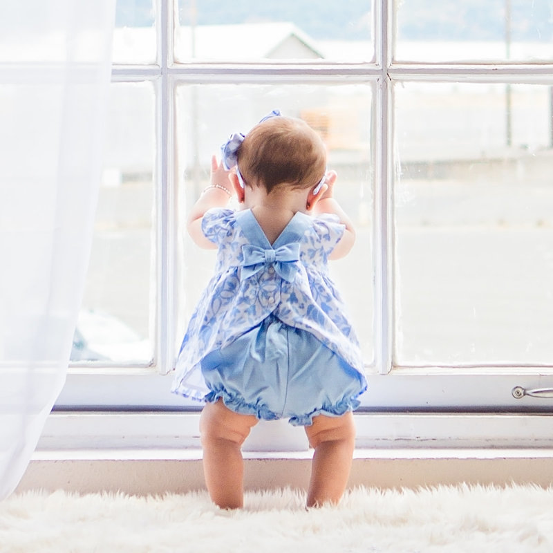 Standing baby at professional baby photography studio  in front of large natural light window