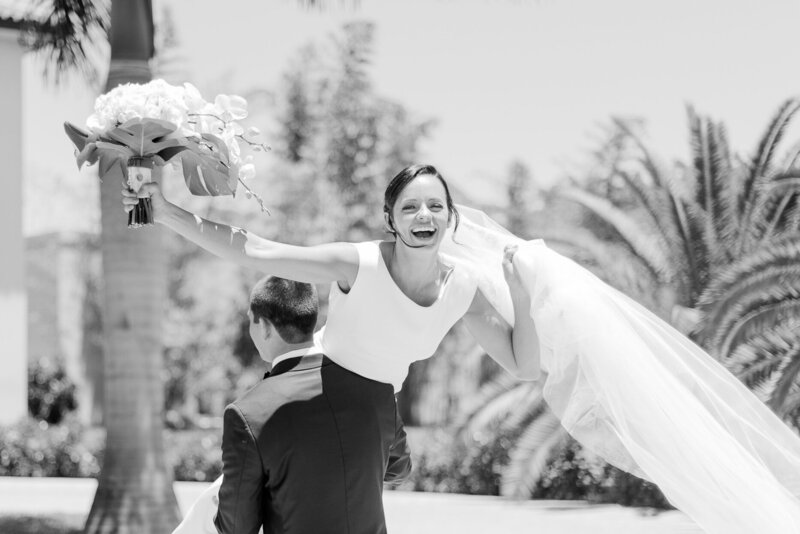 Black and white portrait of groom carrying her bride out of the ceremony