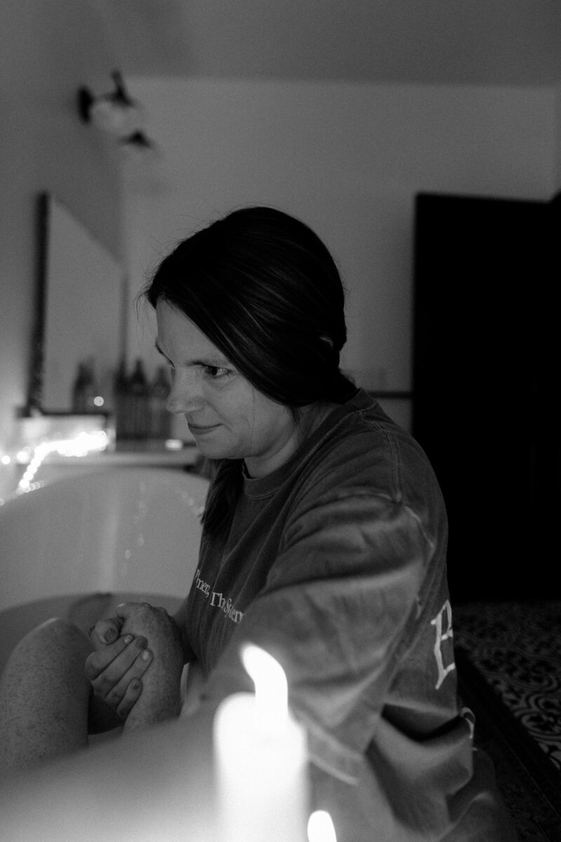 Savannah holding a mother's hand reflecting her dual role as a doula and birth photographer in Utah.