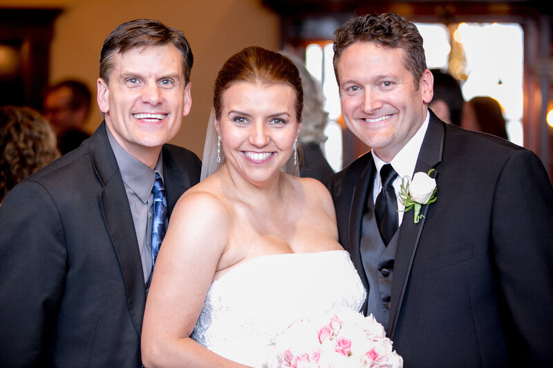Bride and groom smile brightly as they pose with their wedding officiant after their wedding ceremony