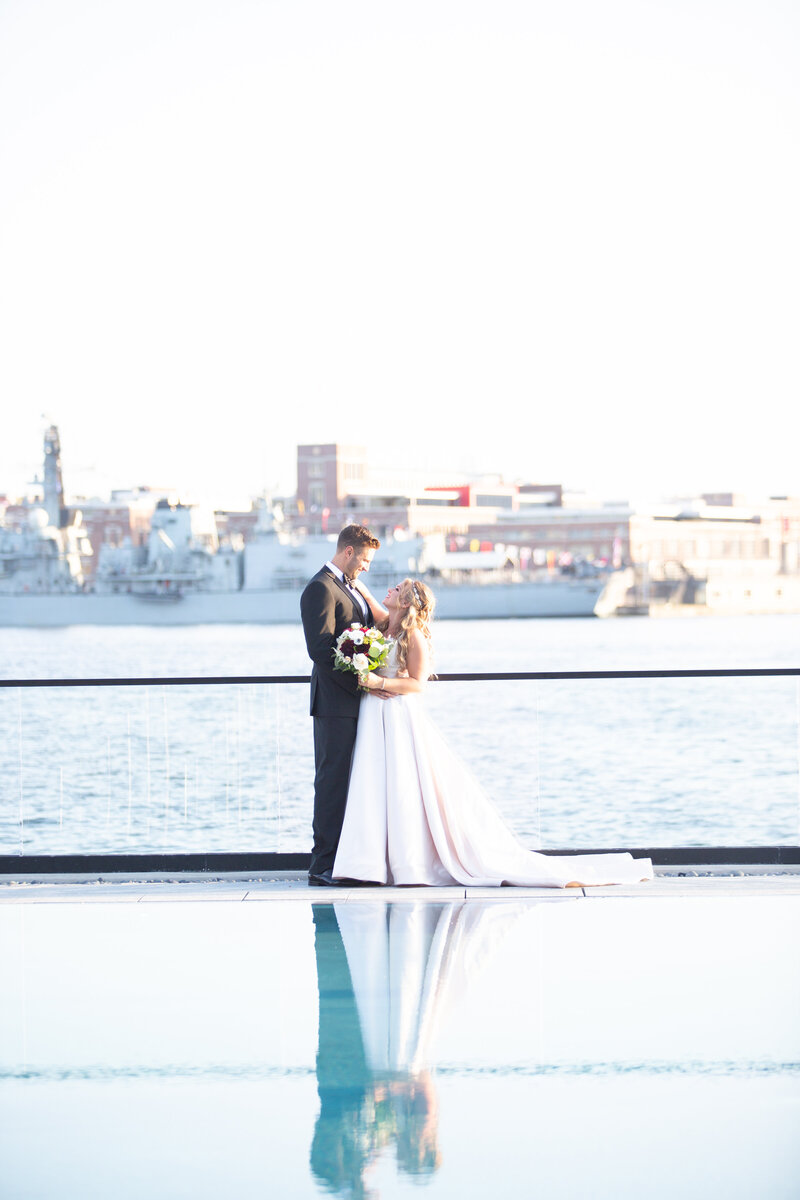 Bride and groom by the pool deck at the Sagamore Pendry  hotel with the Baltimore skyline in the background.
