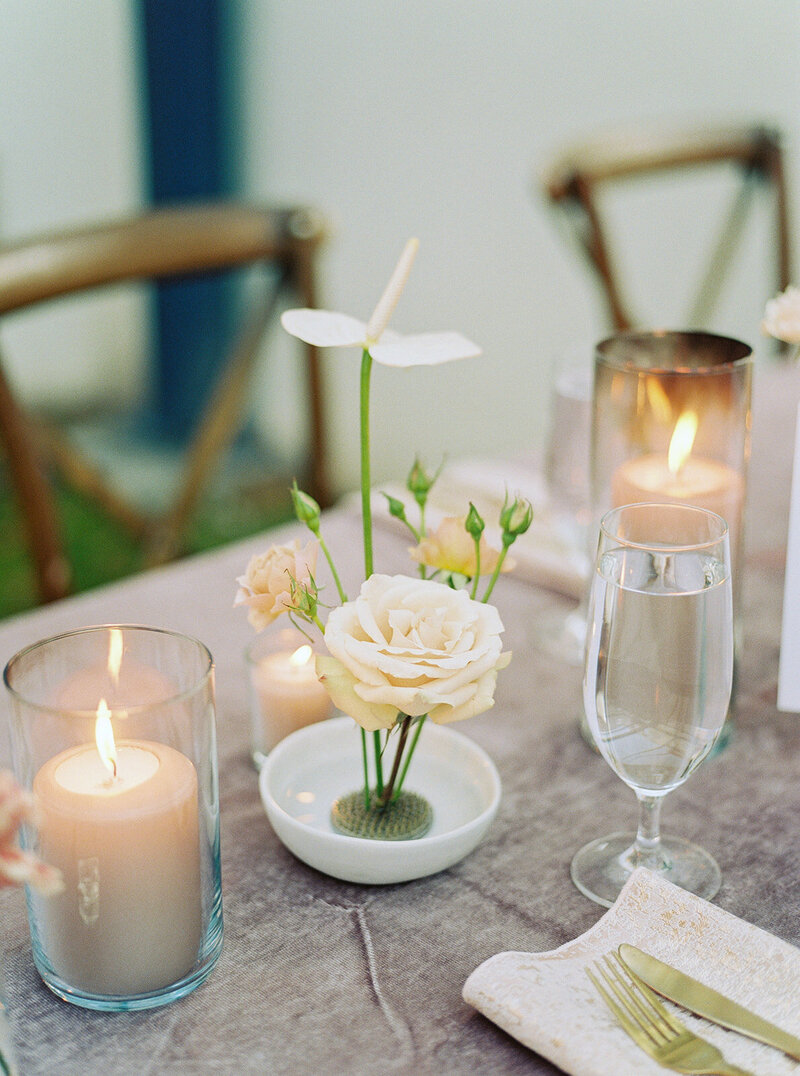 Blush rose modern flower frog arrangement with sandstone pillar candles and velvet table cloth