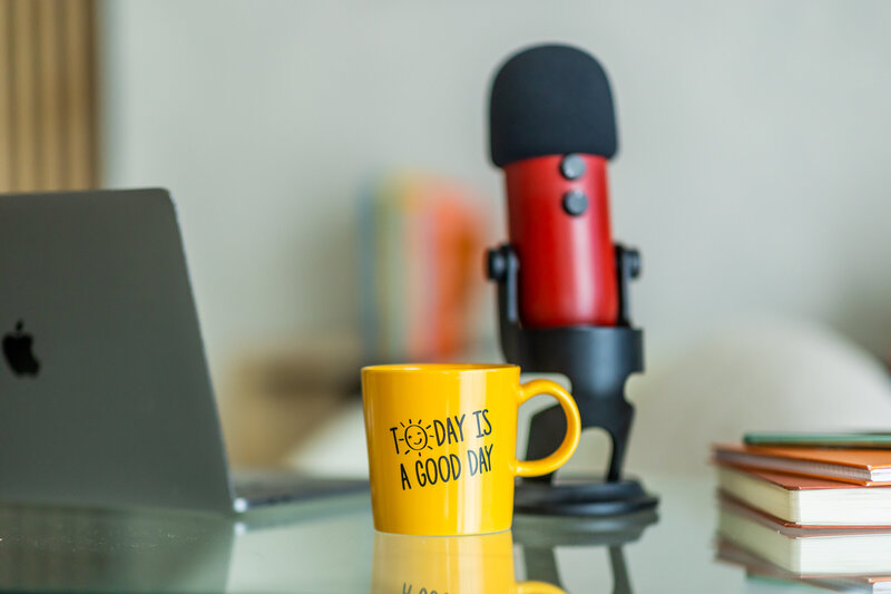 podcast microphone, yellow coffee mug and computer
