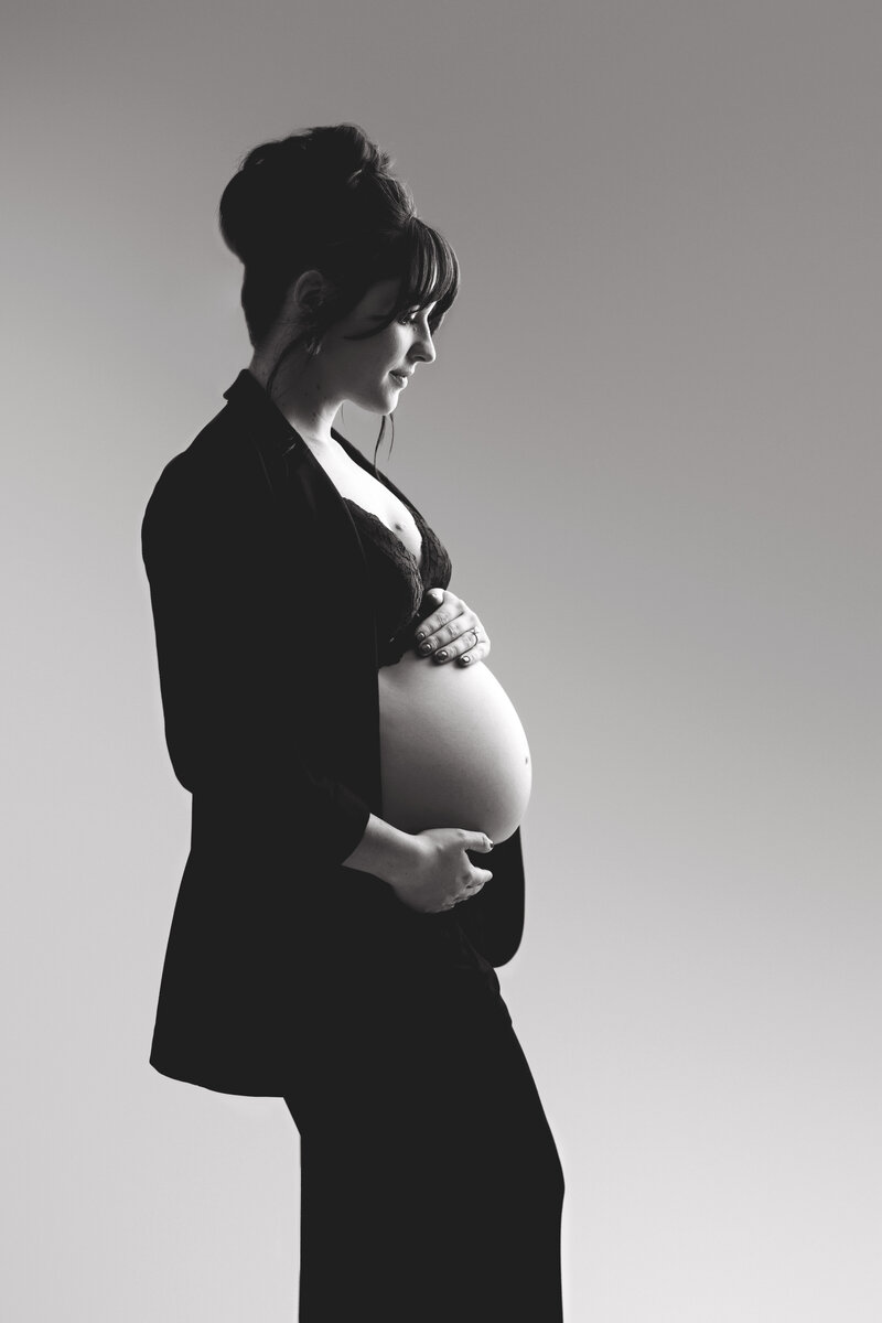 editorial maternity session with mom holding bare belly in black suit jacket in greensburg