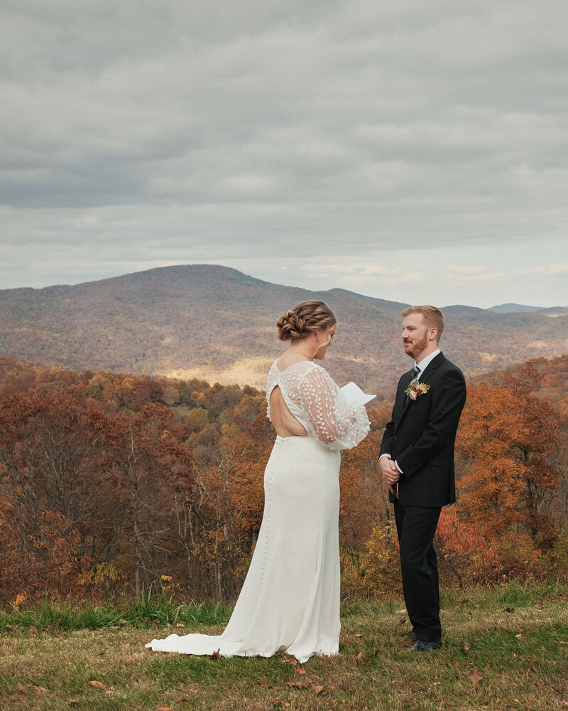 Bride reads her vows to her groom at an overlook in Autumn