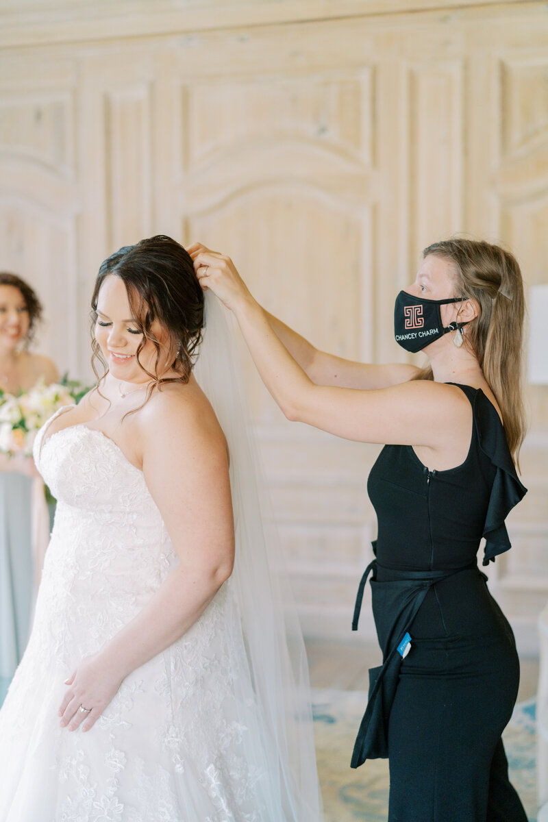 wedding coordinator adjusts bride's veil