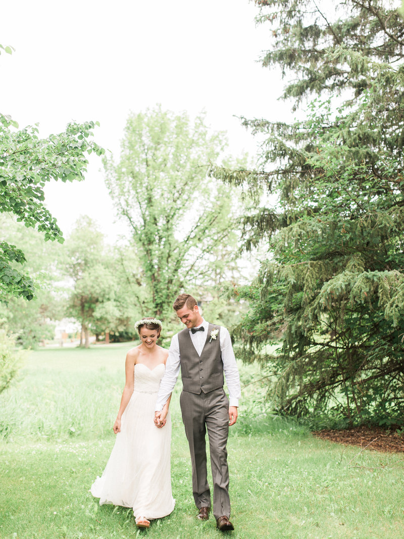 Man in vest walks with bride in a green field