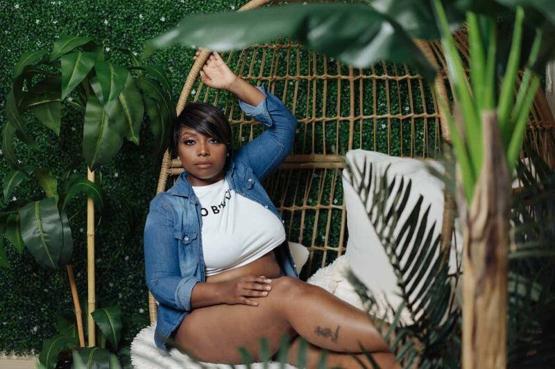 Dark skinned woman posing in rattan egg chair
