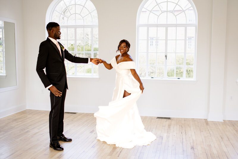 A bride and groom dancing in a white room.