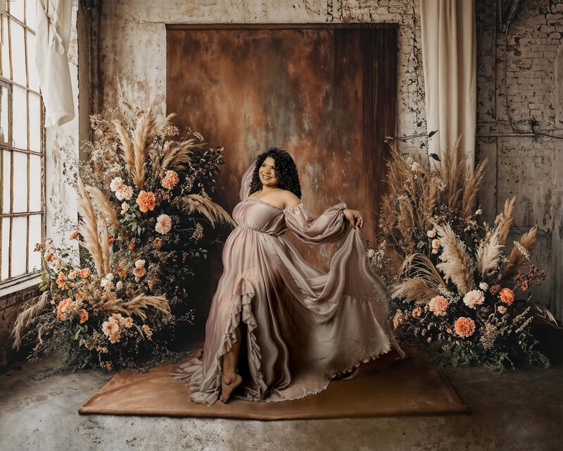 studio image of charlotte mom in brown dress.  she is posed holding dress 