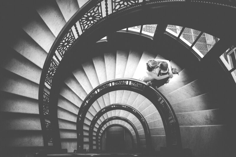 A timeless, black and white image of a bride and groom kissing on the spiral stairs of the Rookery Building in Chicago.