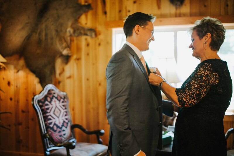 Gatlinburg Photographer Groom and his mother helping get ready before big nashville wedding in a log cabin in the woods