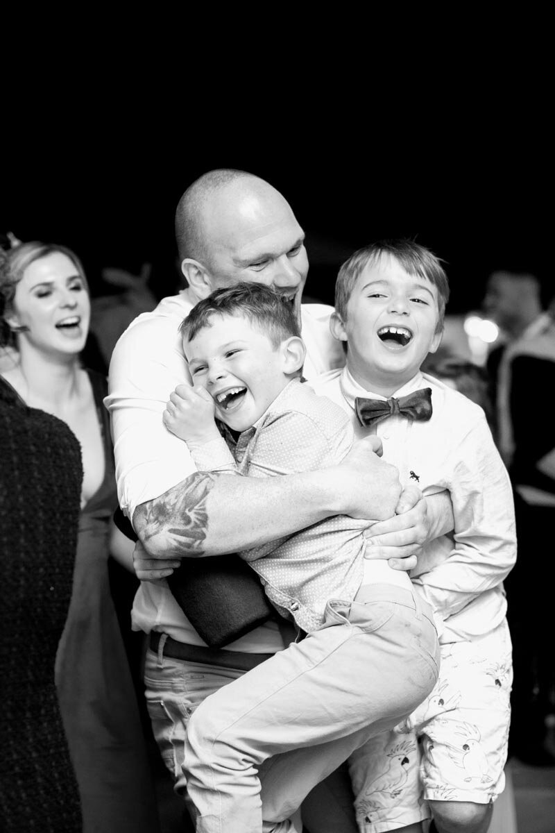 Happy kids carried by dad at wedding reception