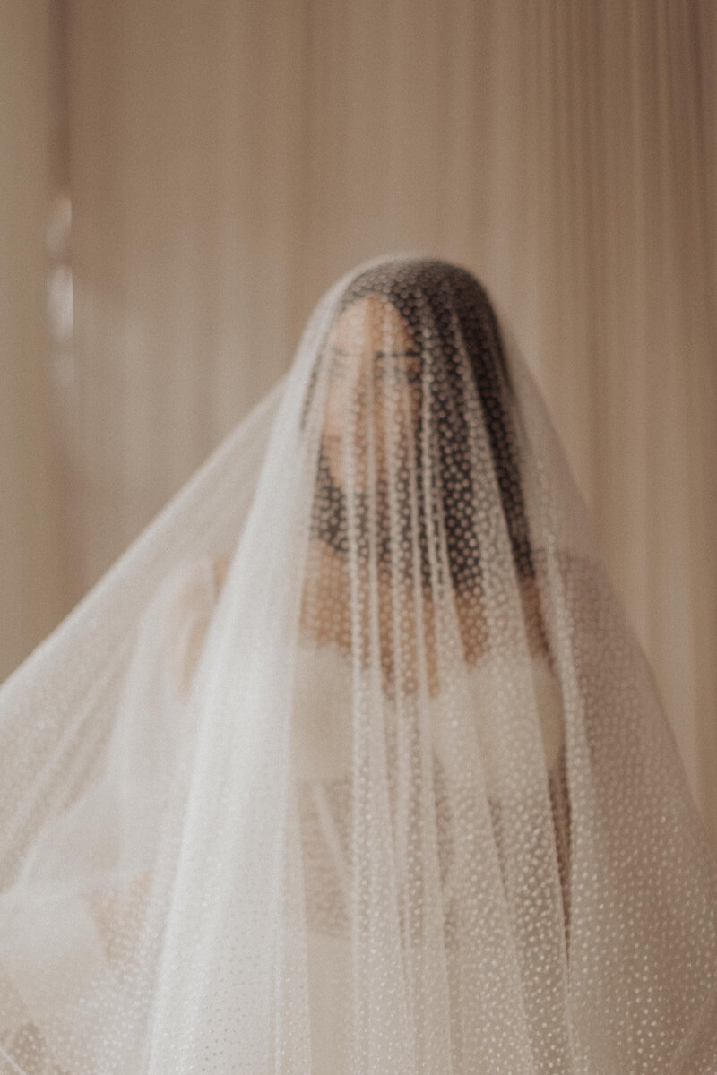 Veiled bride with patterned shadow on her face.