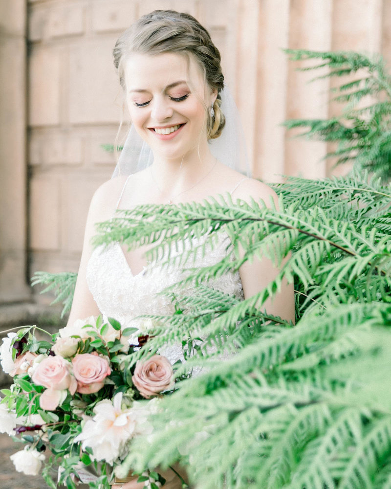 Bride holding bouquet looking down smiling