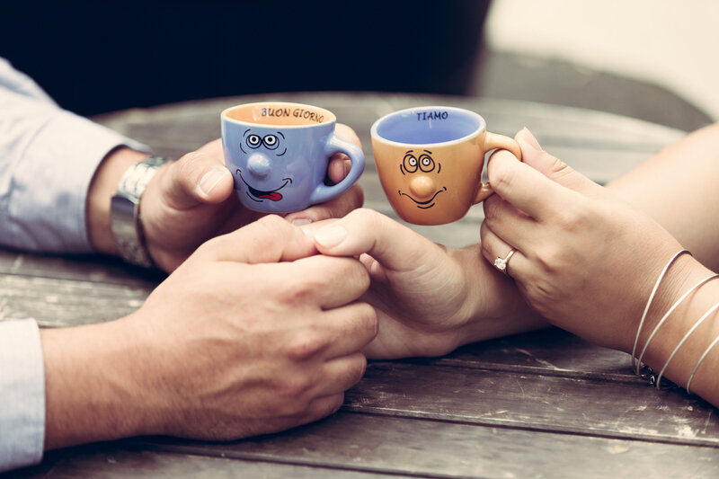A close up photo of a bride and groom holding hands and espresso cups.