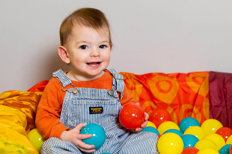 smiling infant boy playing in a ball pit
