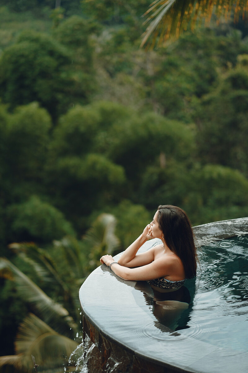 A woman sitting in an infinity pool looking into the distance