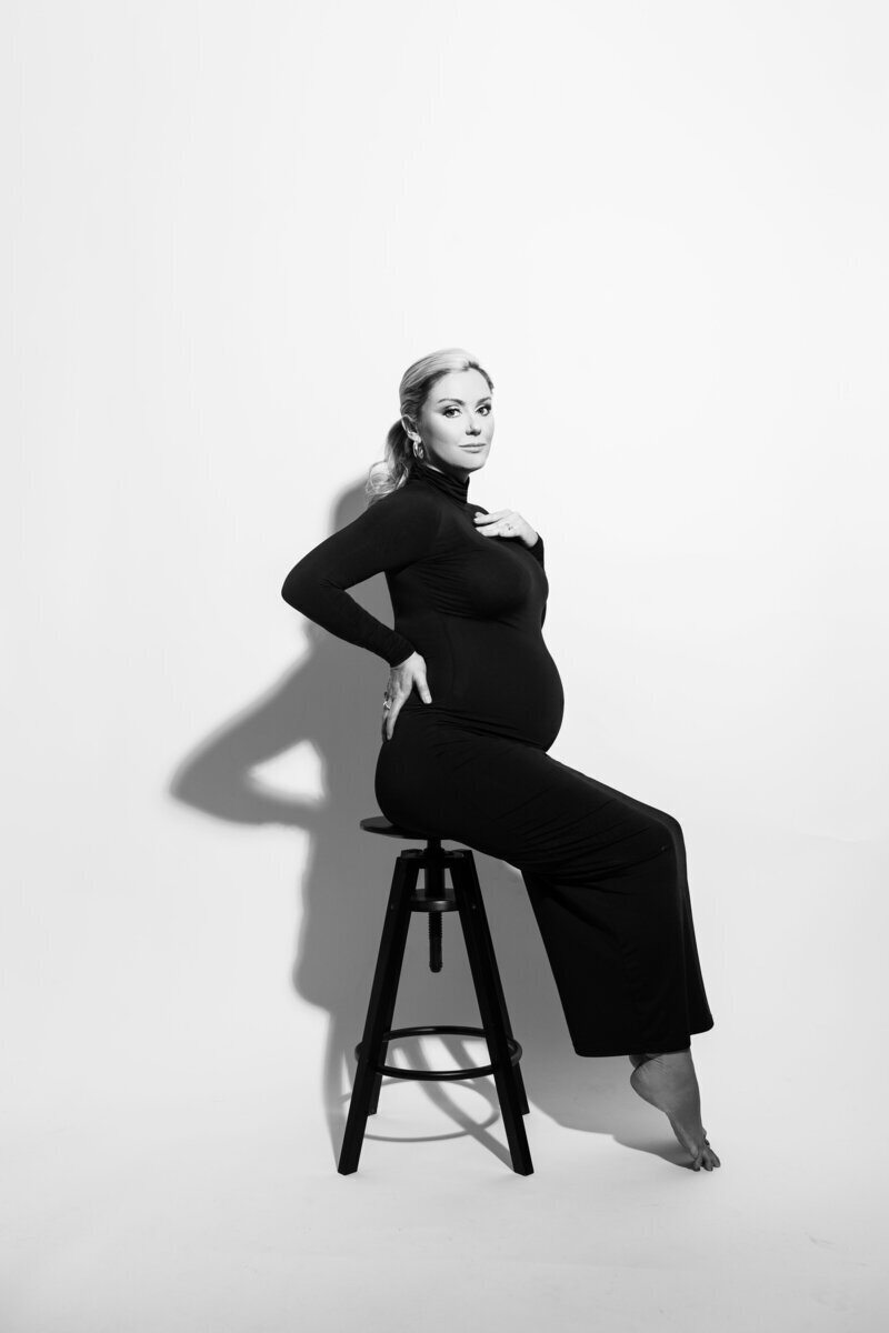 Pregnant woman wearing black sitting on stool taken by maternity photographer nj
