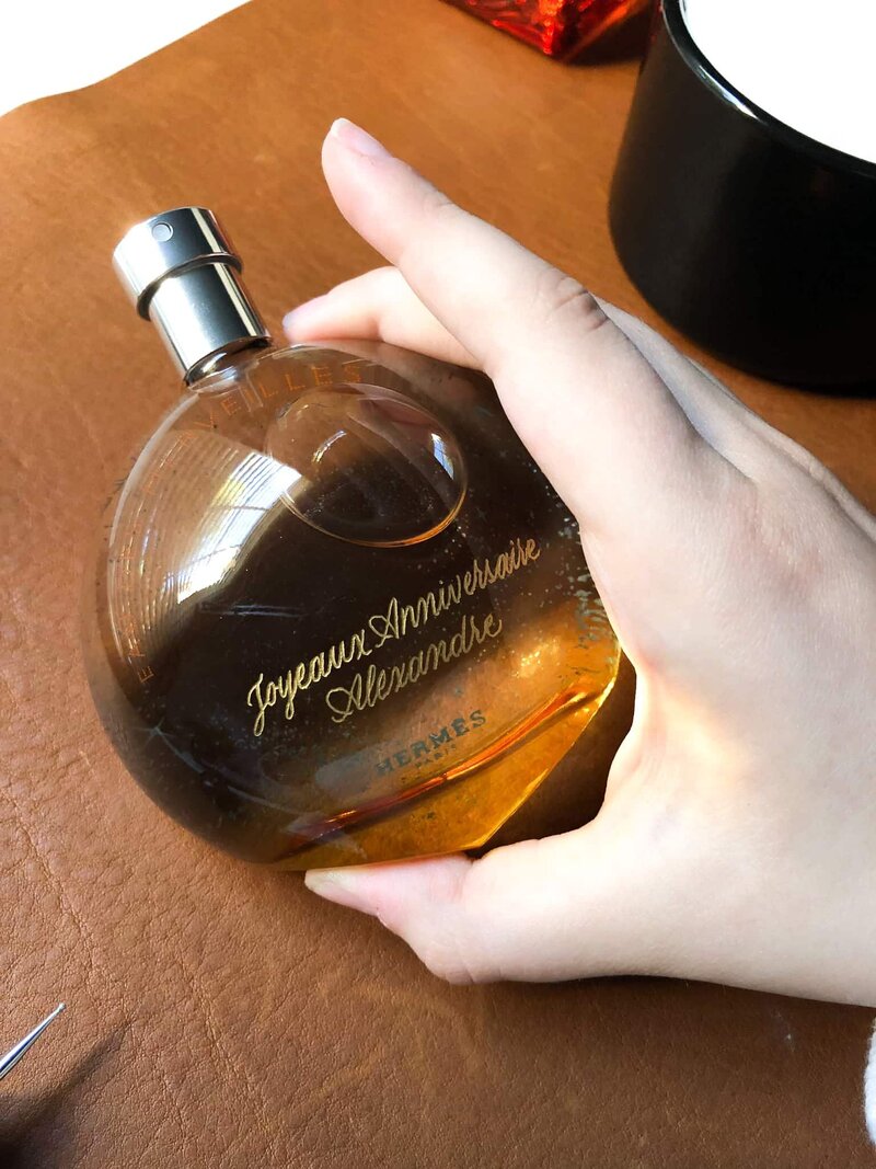 hand holding an engraved Hermes perfume bottle