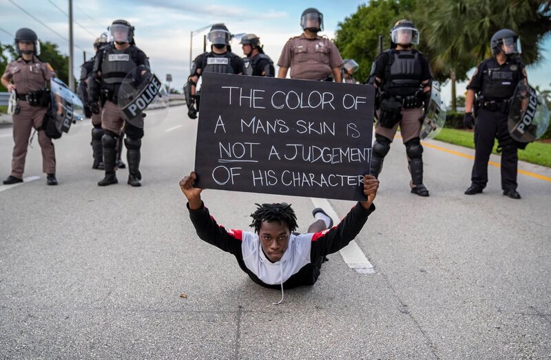 Young man laying on the ground holding sign protesting for black American's rights
