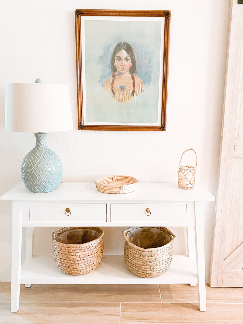 White side table with baskets underneath and frame above