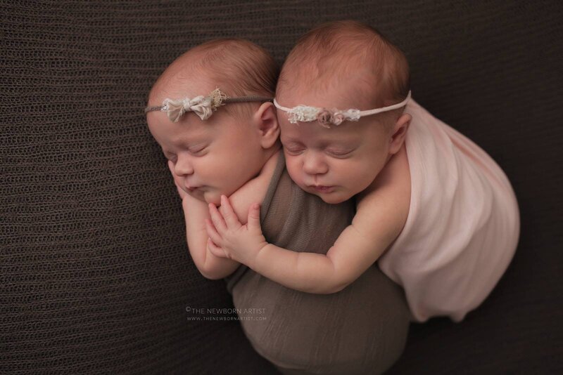 newborn twin girls sleeping with pink and brown wraps and headbands
