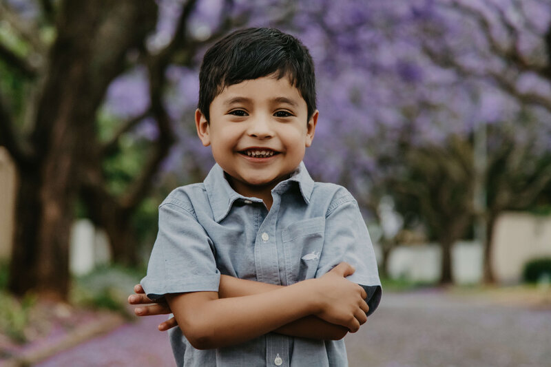 A young boy photographed in front of an avenue of Jacarandas in Rosebank, Johannesburg.