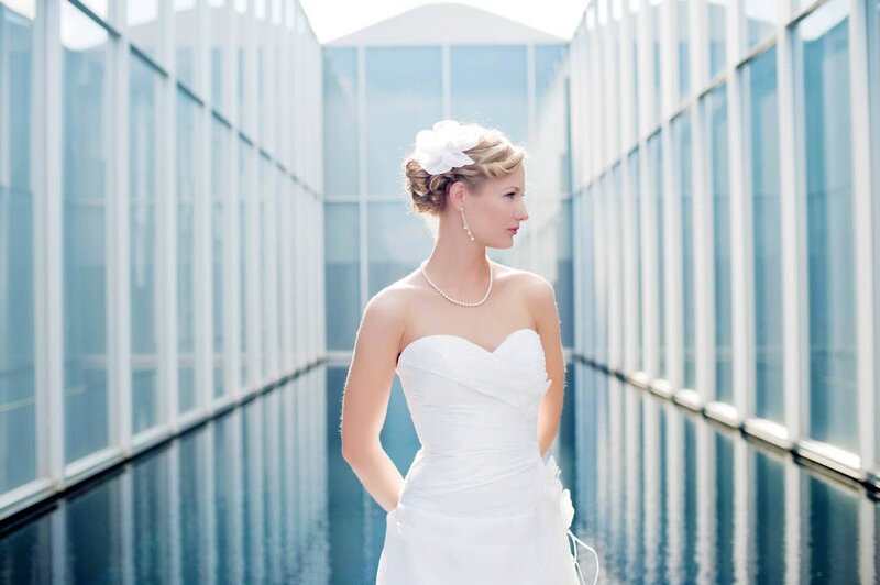 a pretty bride looks away standing in front of a bright blue reflection pool at an art museum
