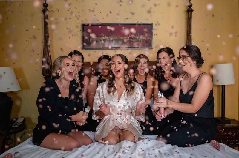 Bridal party pops off confetti on a bed