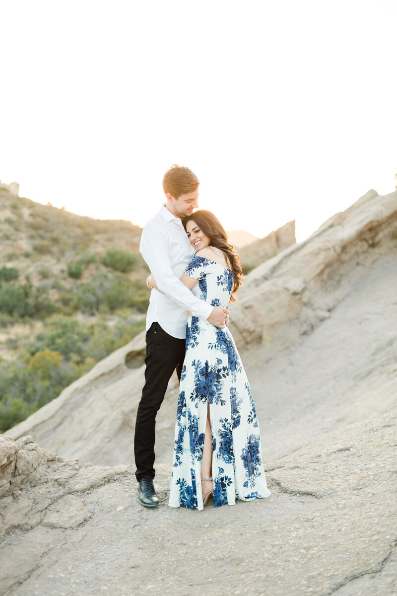 Engaged couple embraces at sunset on a mountainside