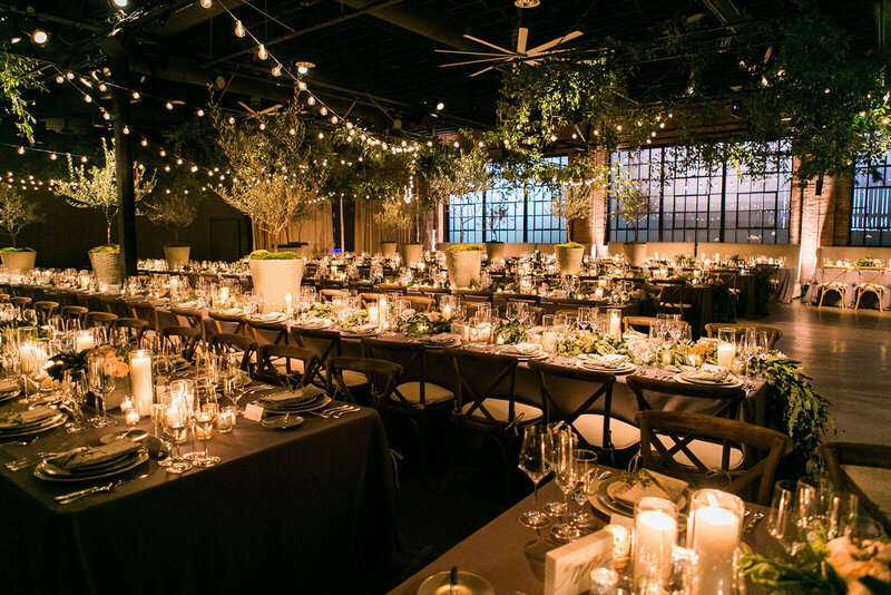 Warehouse transformed into Italian wedding reception with olive trees.