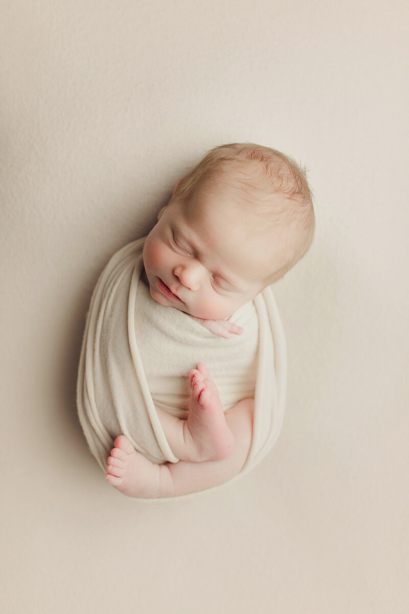 newborn baby in cream wrap