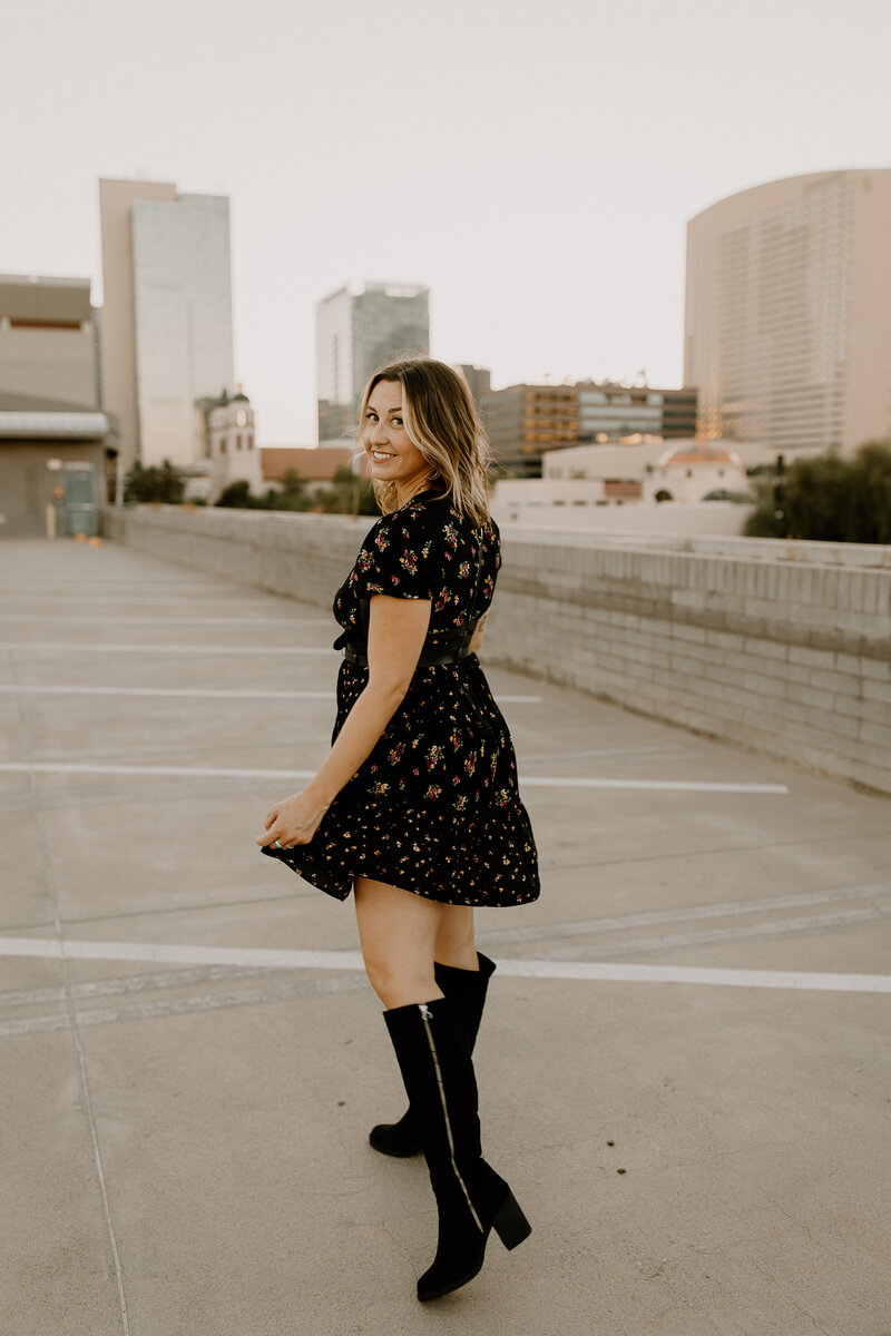 A woman looking back and smiling as she walks on the roof of a parking garage.