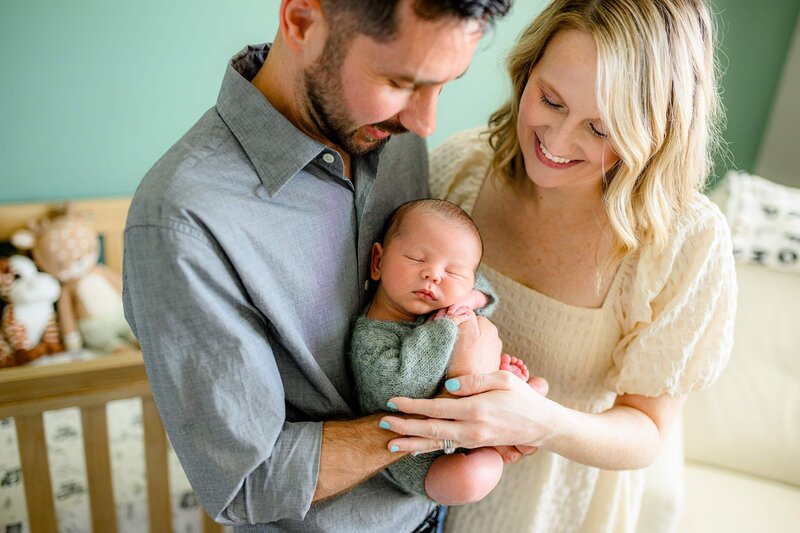 father holds his newborn son while mother snuggles in with them