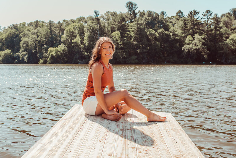Woman sitting cross legged on a dock smiling