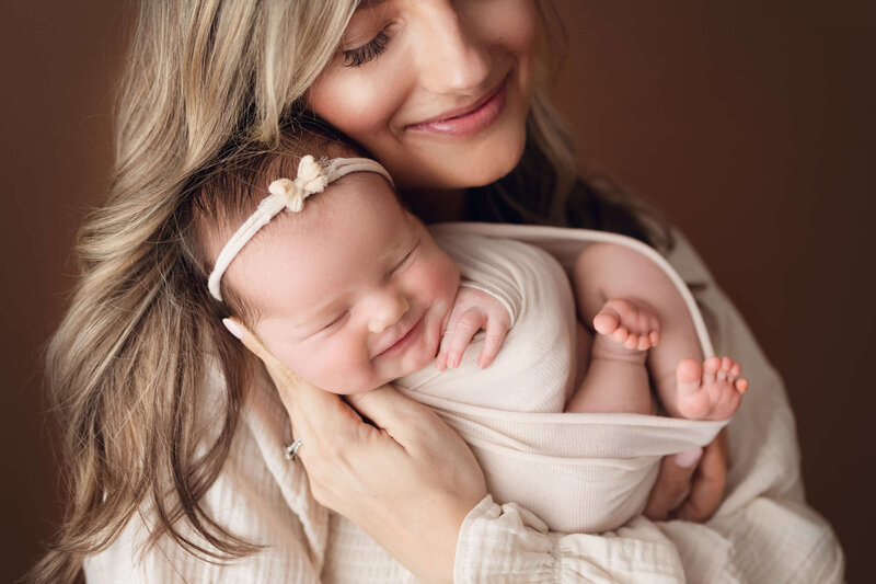 mom and newborn baby smiling with eyes closed