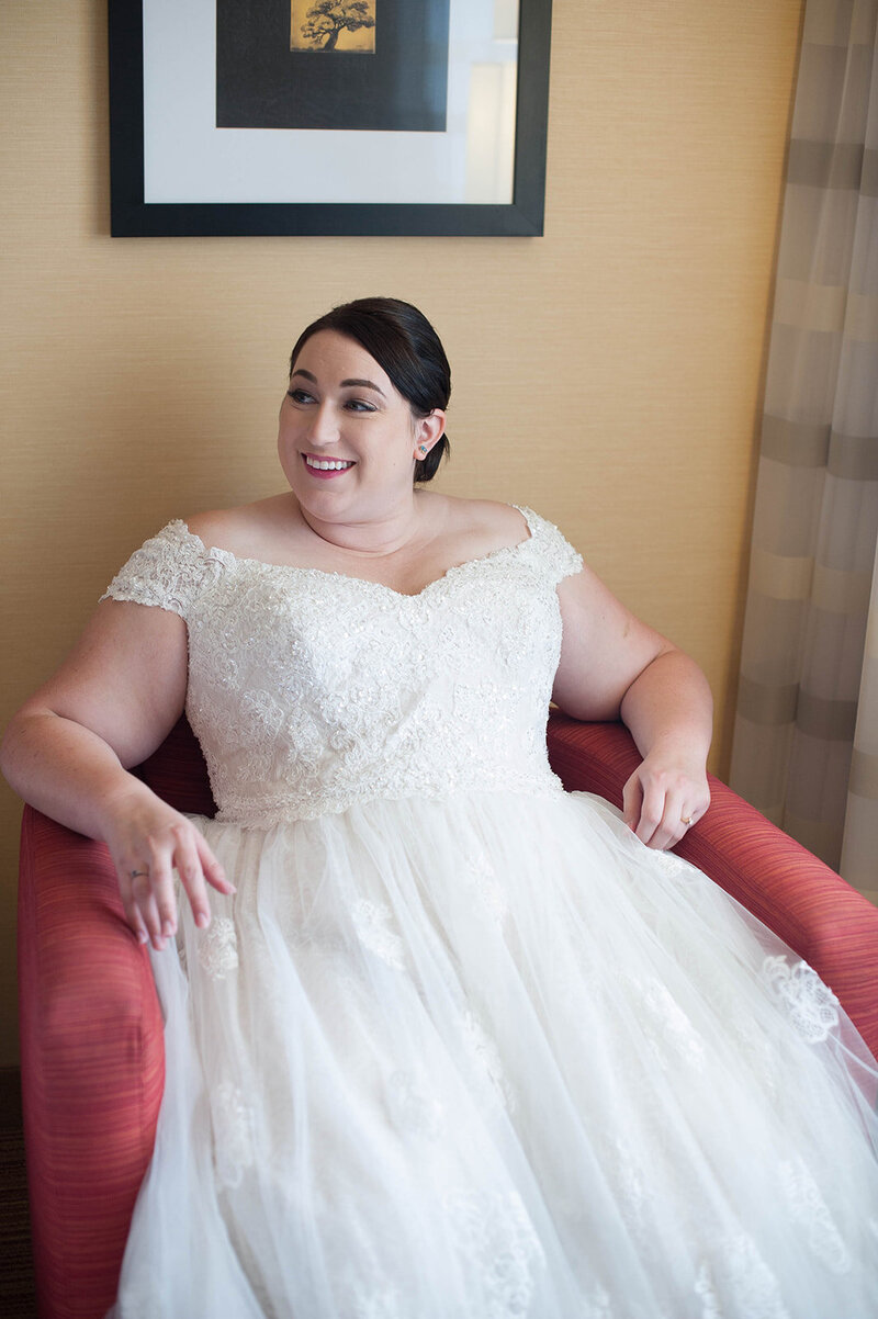 Plus size bride sits and smiles before her raleigh wedding