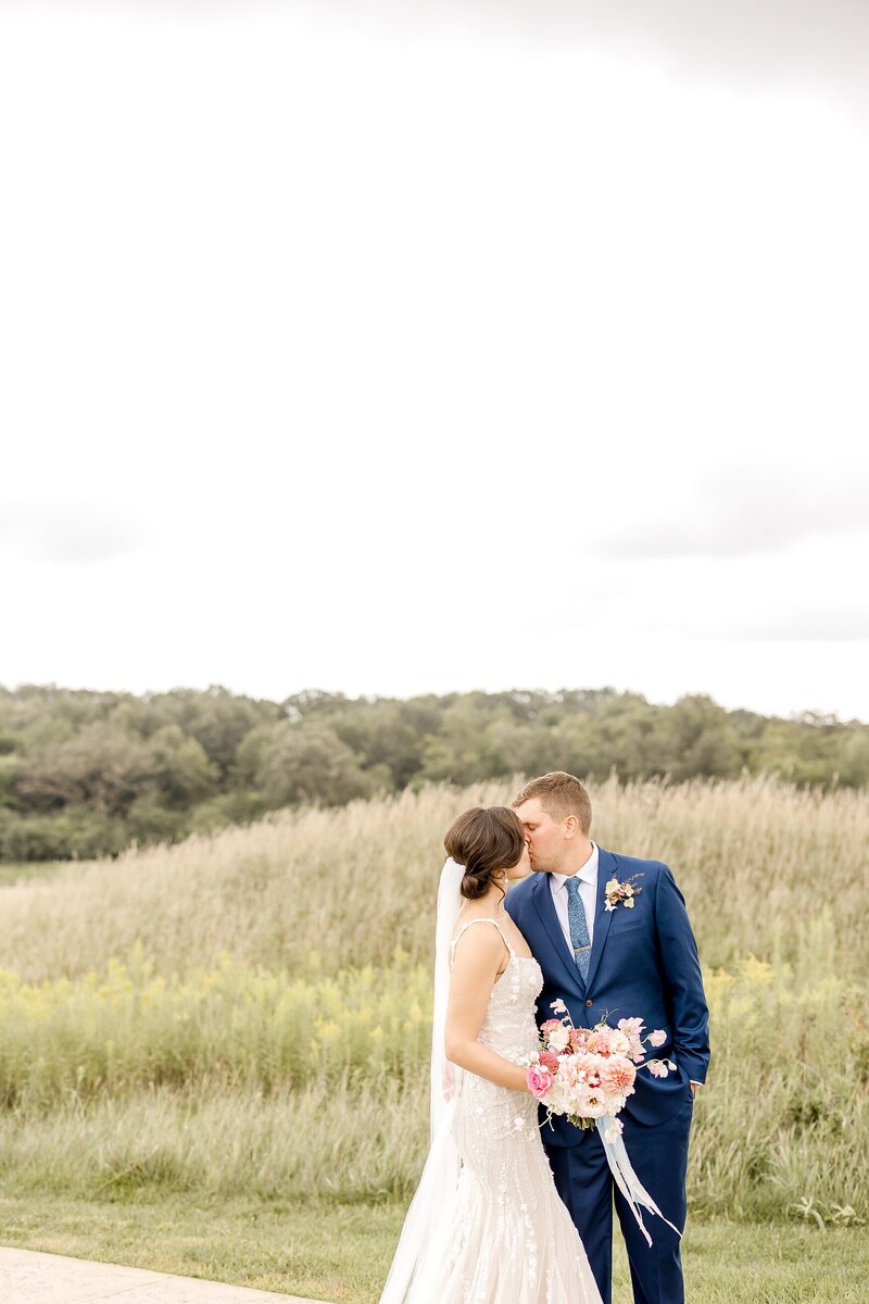 bride and groom kissing in wild grass field