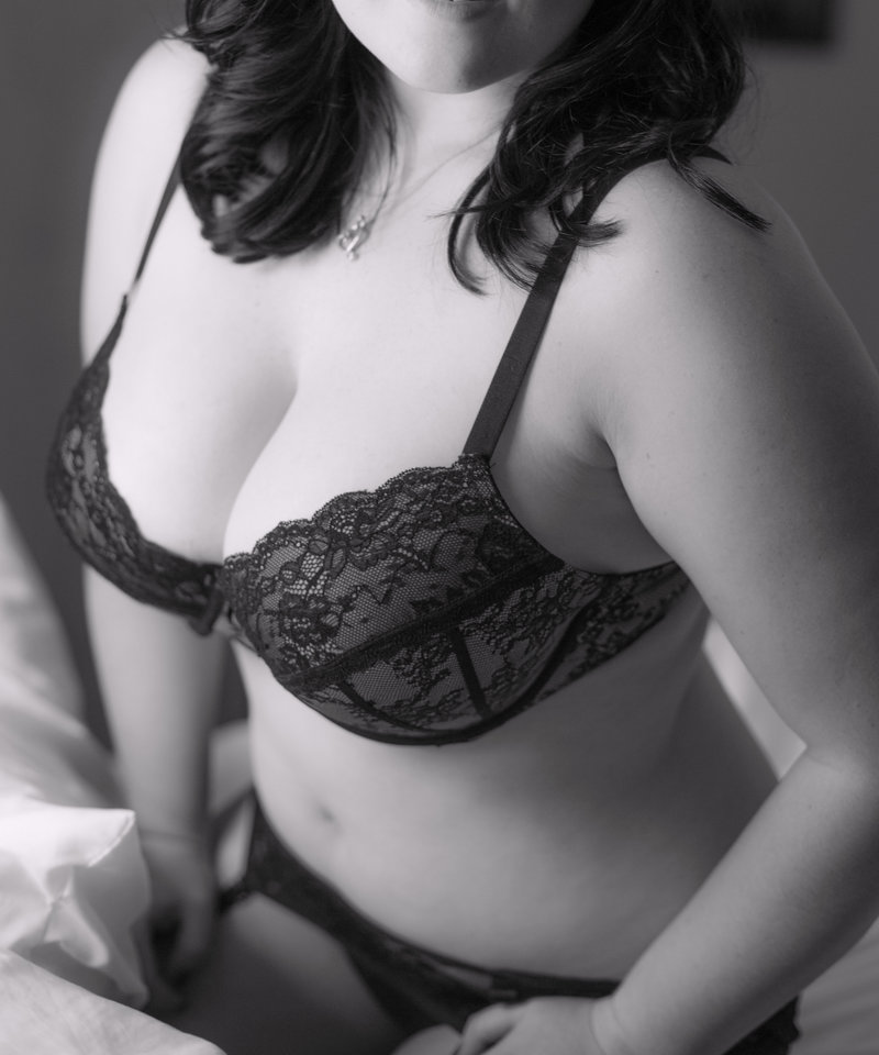 sexy black and white boudoir photo pic of plus size curvy woman with dark hair in bed in black lace bra and panties