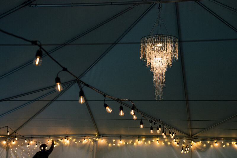 Warm string lights and chandelier glowing inside wedding tent at night, captured by wedding photographer Niko Coric - Lumen Clarity Media