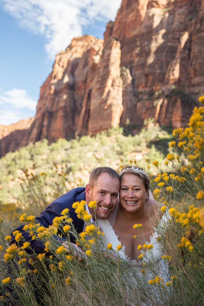 Bride and Groom smile through a field of yellow flowers on their elopement day.