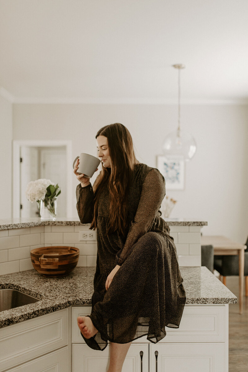 Copywriter sitting on the kitchen counter sipping coffee