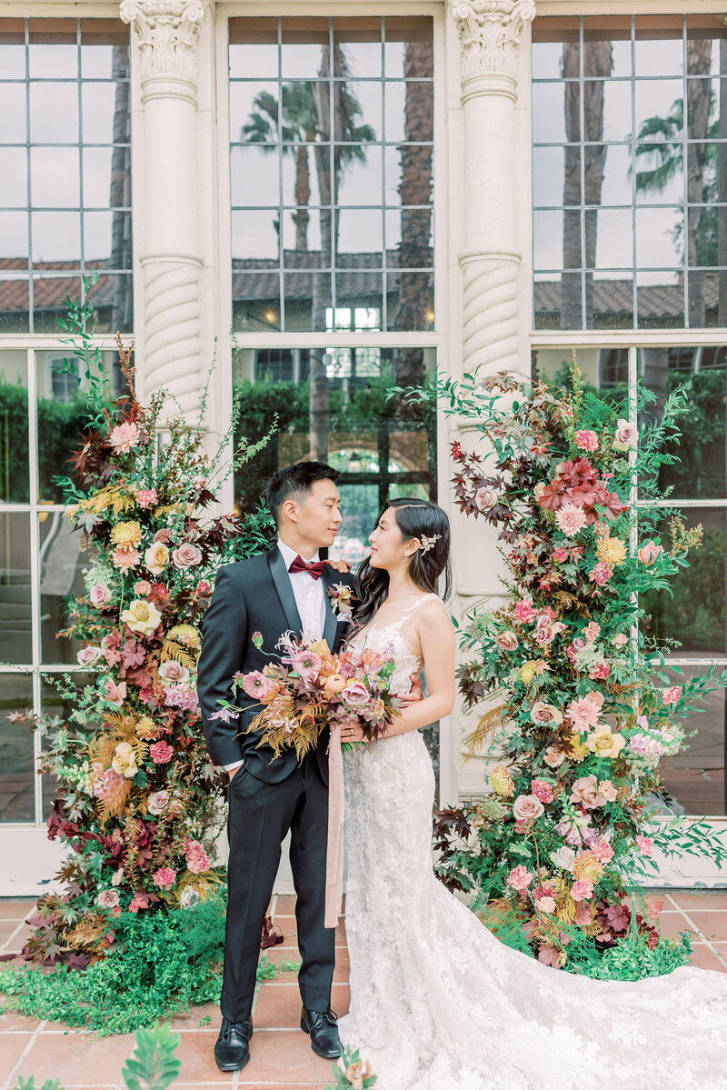 18-alisonbrynn-Radiant-LoveEvents-Maxwell-1-House-bride-groom-adoringly-looking-at-one-another-in-alter-floral-columns-behind-outdoors-romantic-elegant-timeless-romantic-elegant-timeless