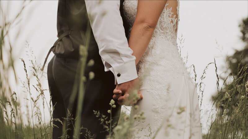 Bride and groom hold hands at an outdoor wedding