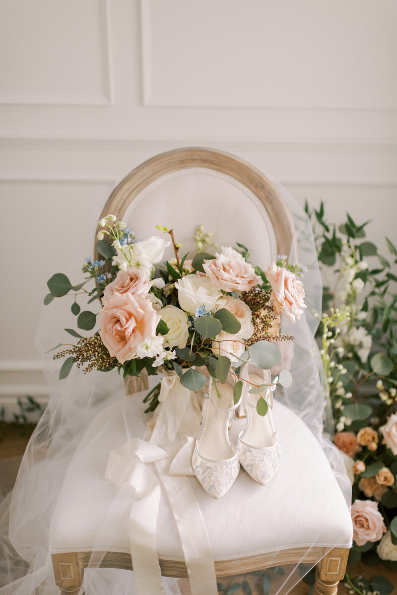 Bridal bouquet and lace wedding shoes on rustic chair