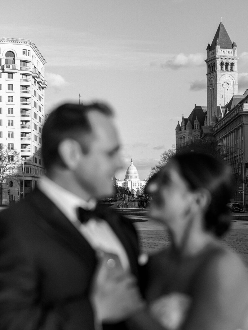 BRide and groom look at eachother with Capitol in the background