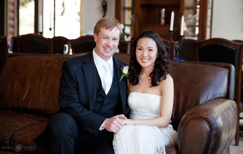 Couple poses for a portrait while sitting on nice leather couch at their private rental home at their wedding elopement at Narrow Trail Ranch in Estes Park